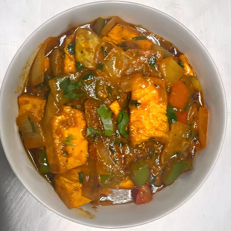 Indian paneer dish with bell peppers, onions, and herbs in a rich orange sauce.