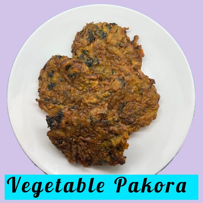 Three golden-brown, crispy vegetable pakoras are served on a white plate.